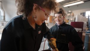 Student casting metal and working in the Metals Studio with instructor