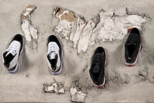 Two pairs of basketball sneakers atop a concrete slab holding two confederate jackets