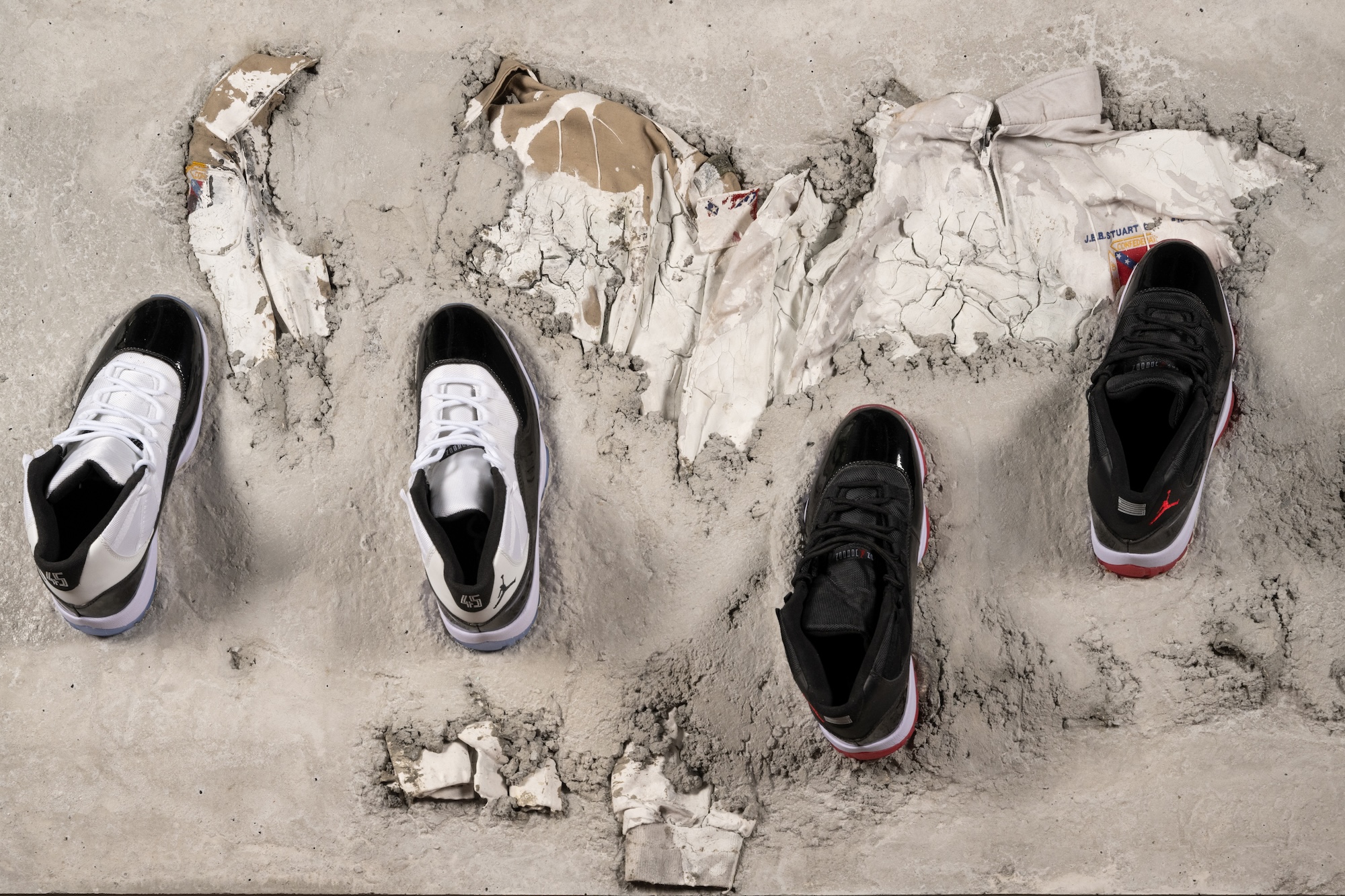 Two pairs of basketball sneakers atop a concrete slab holding two confederate jackets