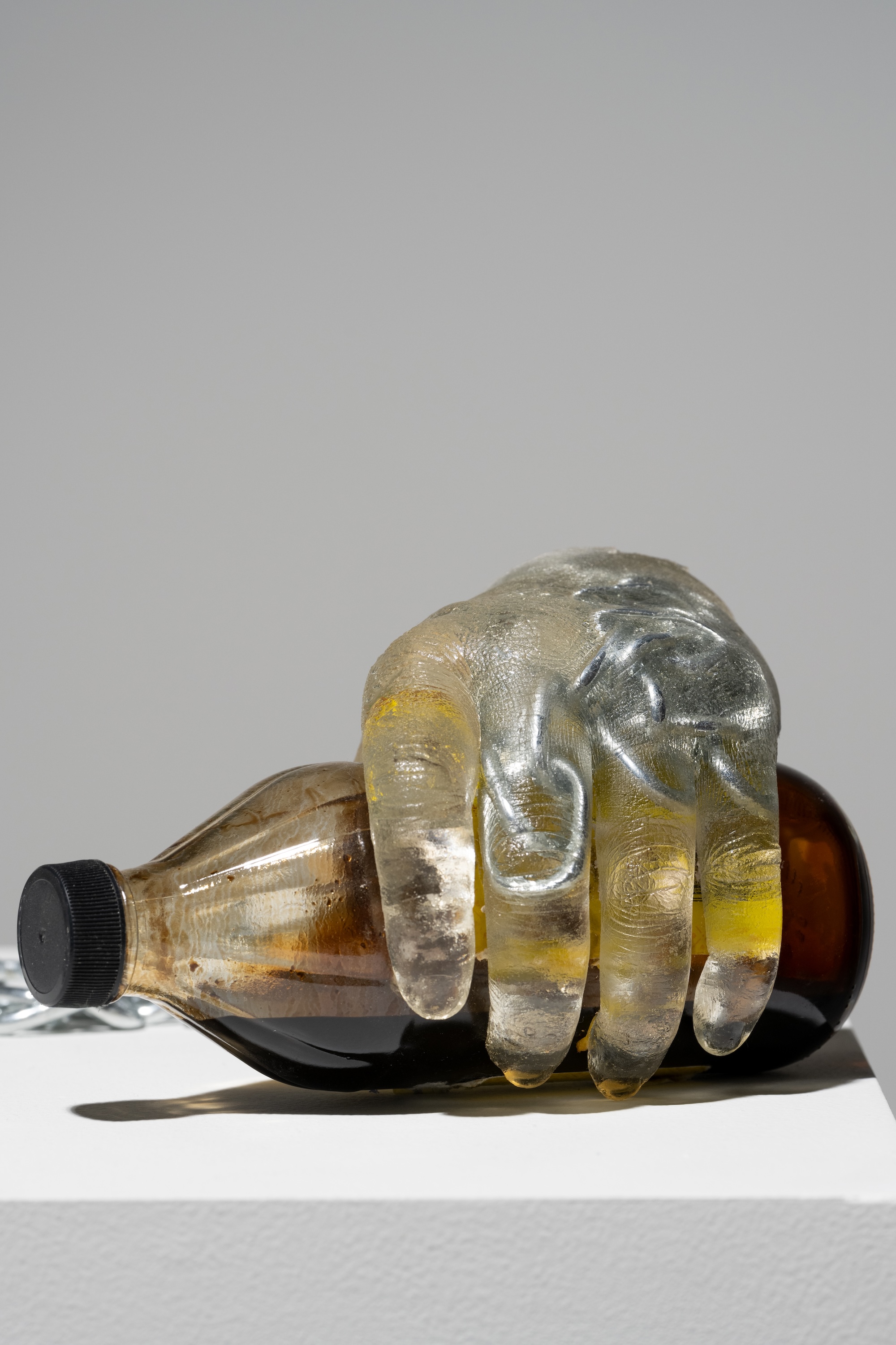 resin hand holding a molasses bottle