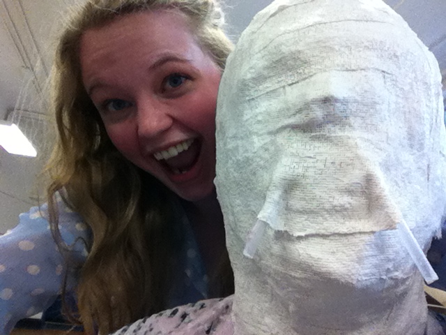 girl smiling next to plaster mask