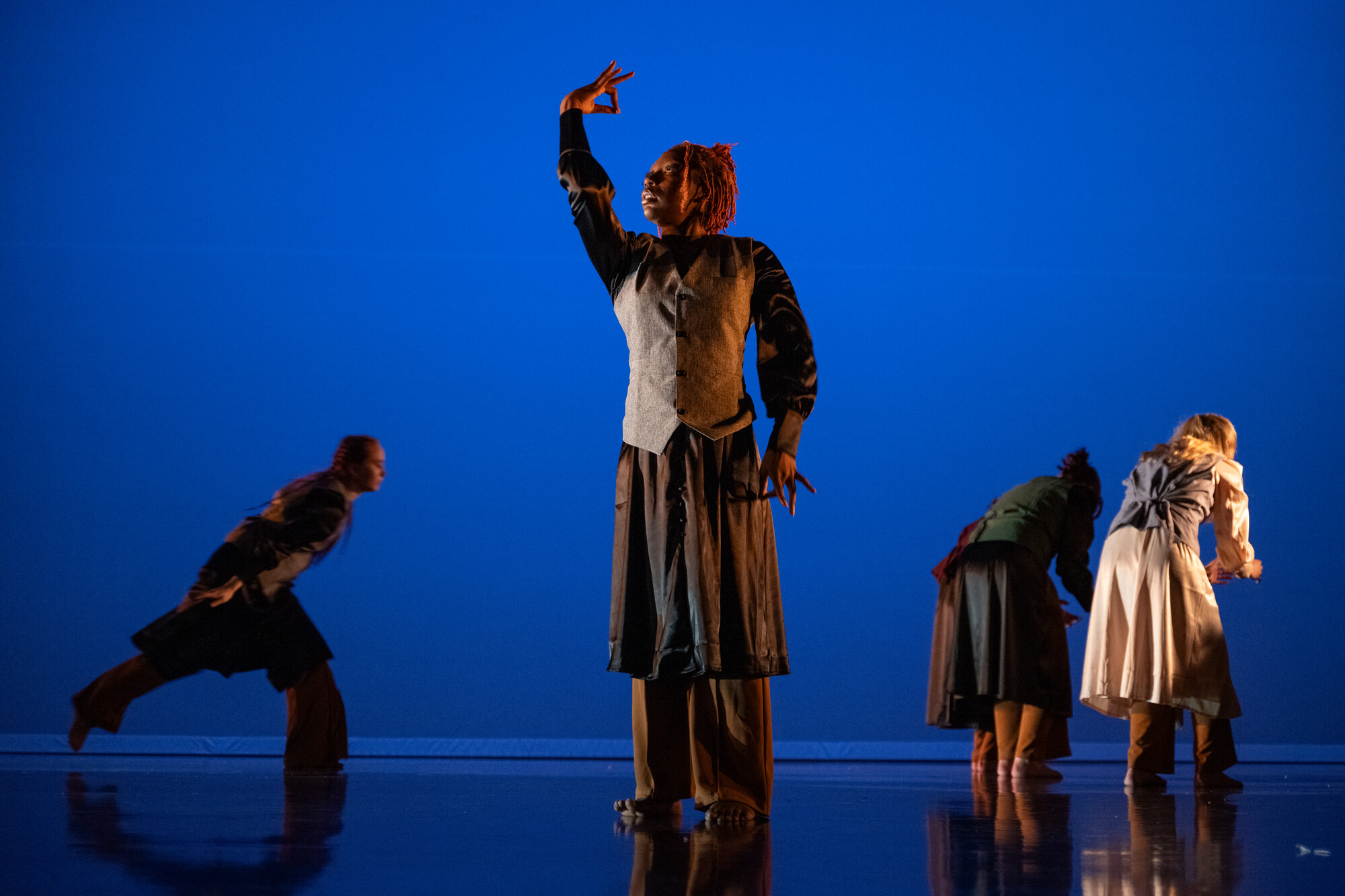 students performing dance now on a dark stage with blue lighting