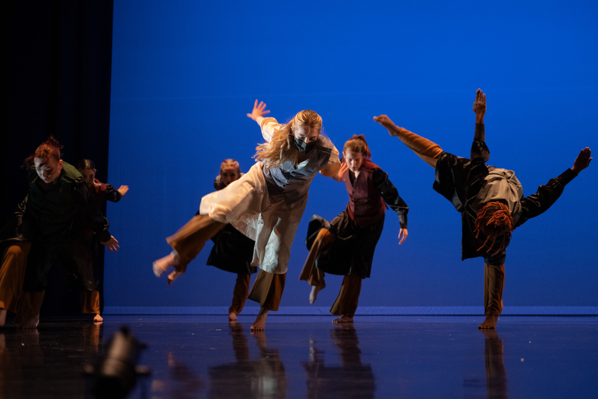 students performing dance now on a dark stage with blue lighting