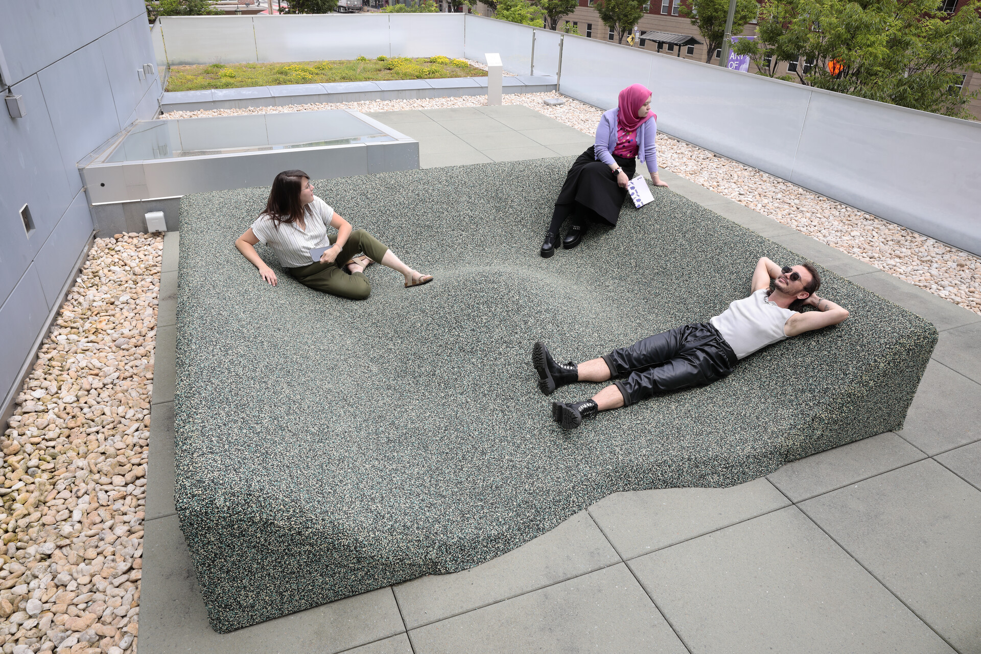 3 people reclining in the lounge pit made of recycled rubber installed on the roof of the ICA at VCU