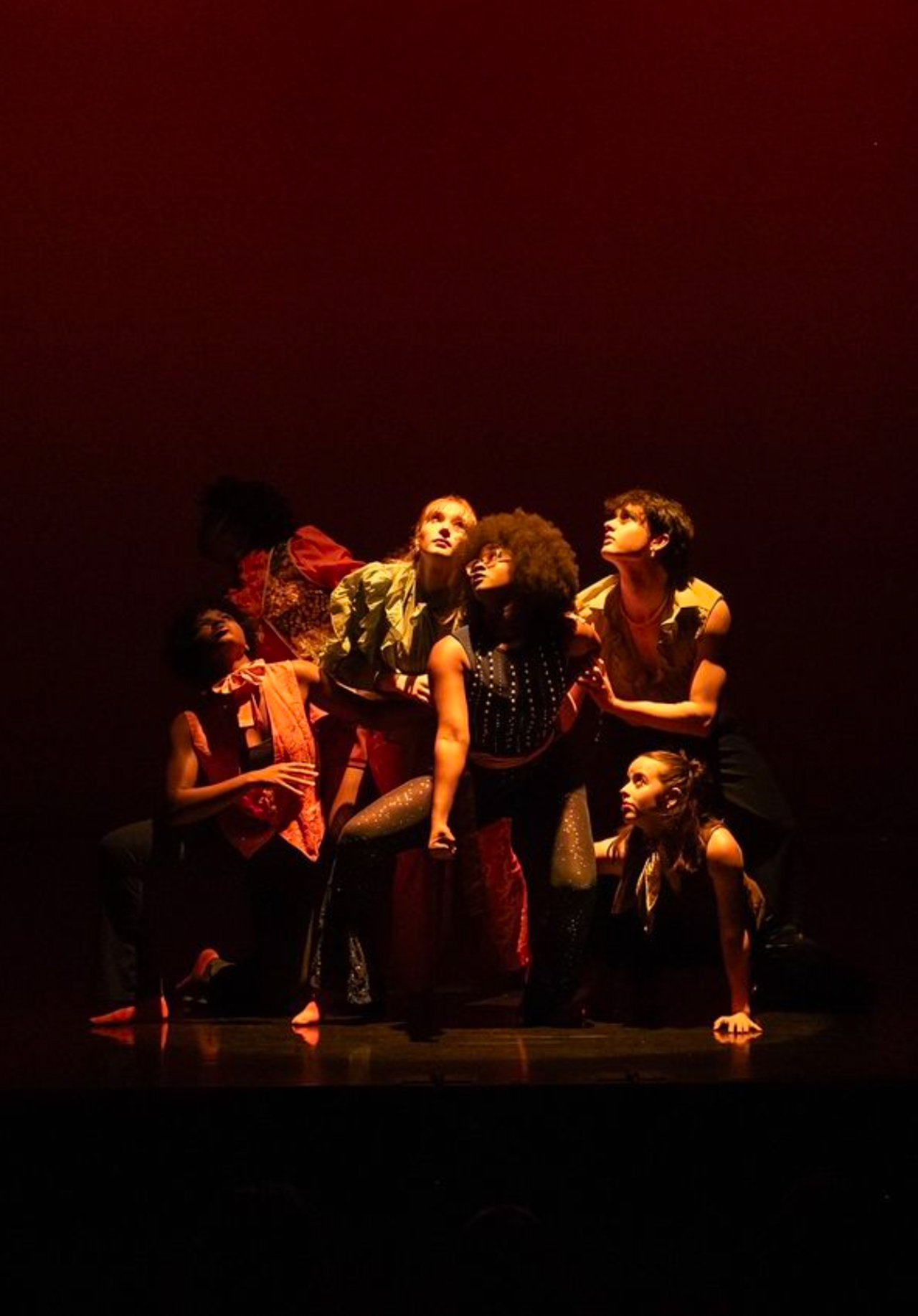 Students performing a dance at INTER9 on a dark stage with red lighting