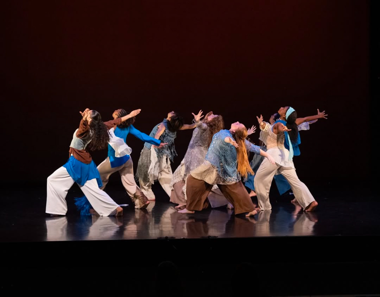 Students performing a dance at INTER9 on a dark stage with red lighting