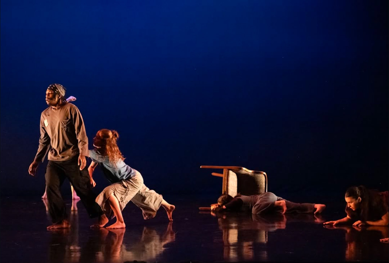 Students performing a dance at INTER9 on a dark stage with blue lighting