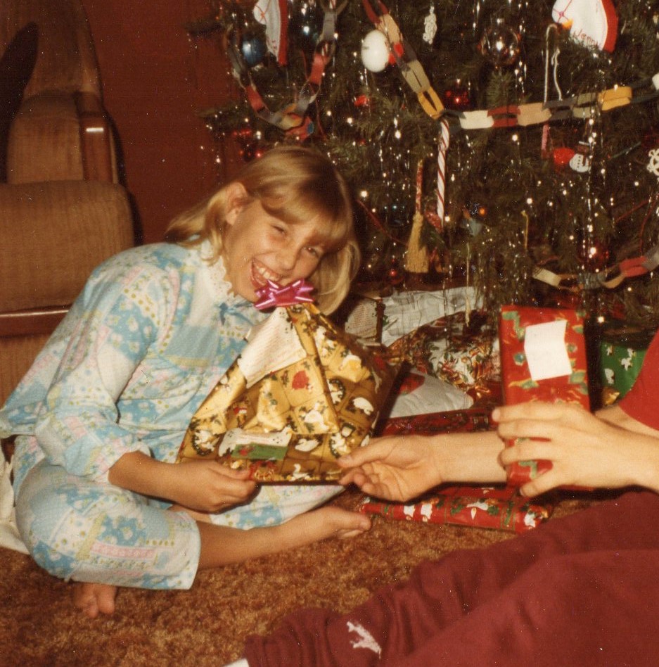 girl opening present by christmas tree