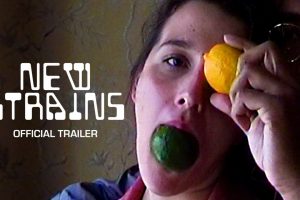 title card for the film New Strairs showing a couple's faces with a man in the background holding a lemon in front of the womans eye in the foreground while she is holding a lime in her mouth