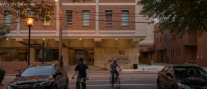 Partial view of Pollak building with students riding bikes