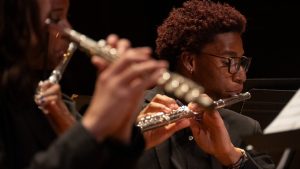 The Symphonic Wind Ensemble and University Band performing together and a student playing the flute