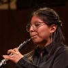 A student plays the oboe on stage during a concert