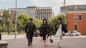 students with cap and gown walking down street