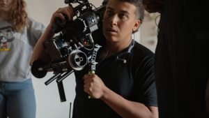 Cinema student holding video camera on set