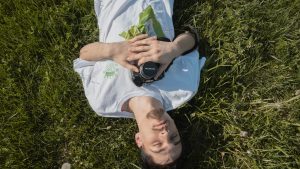 photo student laying in the grass with camera around his neck