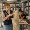 A ceramics student works on a large scale piece in the studio during class