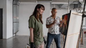 A professor talks with a student about her painting in a studio