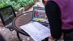 graphic design student working on laptop designing a colorful mural