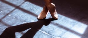 Close up of a ballet dancer's feet, one crossed over the other in dramatic lighting