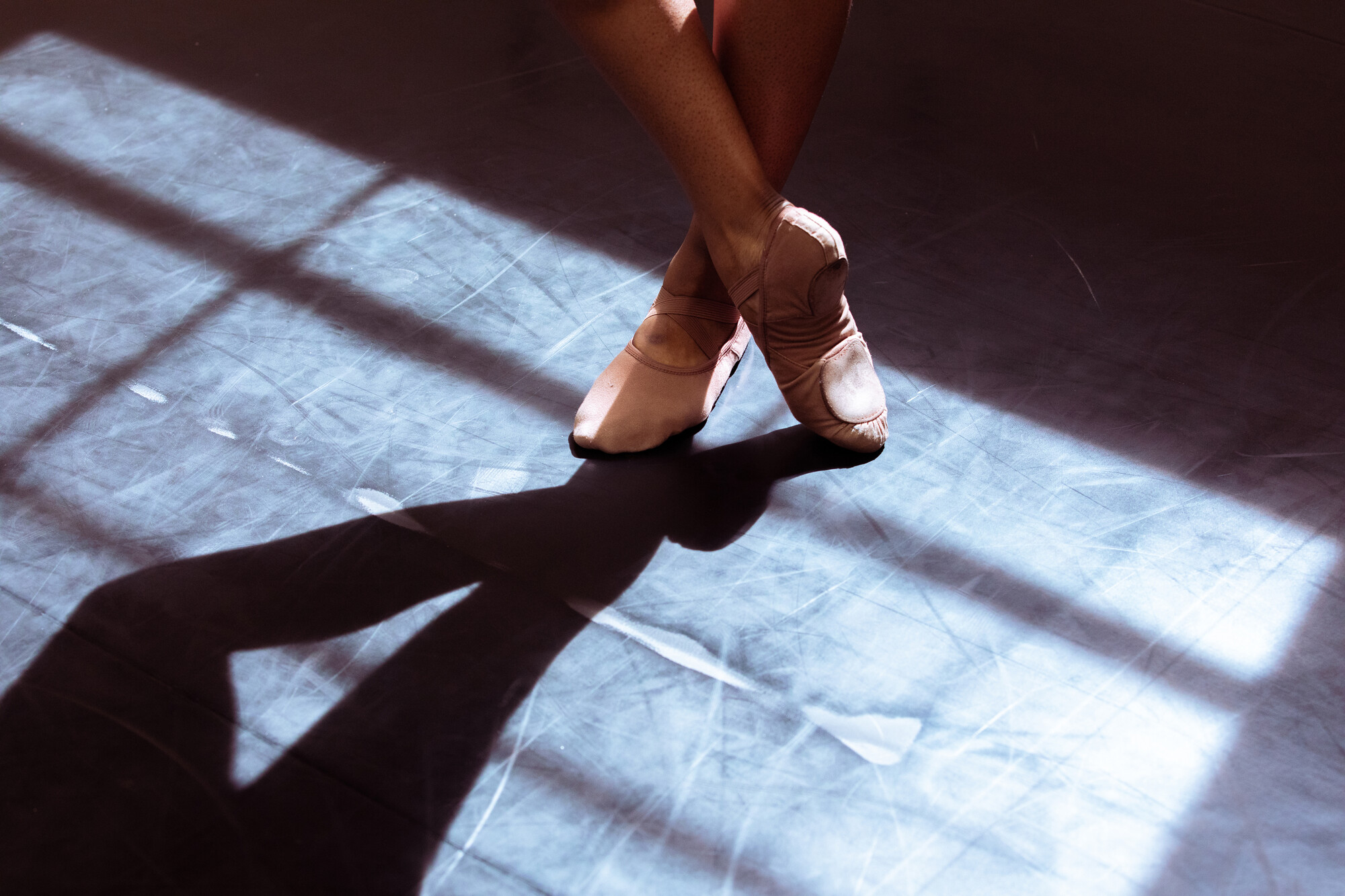 Close up of a ballet dancer's feet, one crossed over the other in dramatic lighting