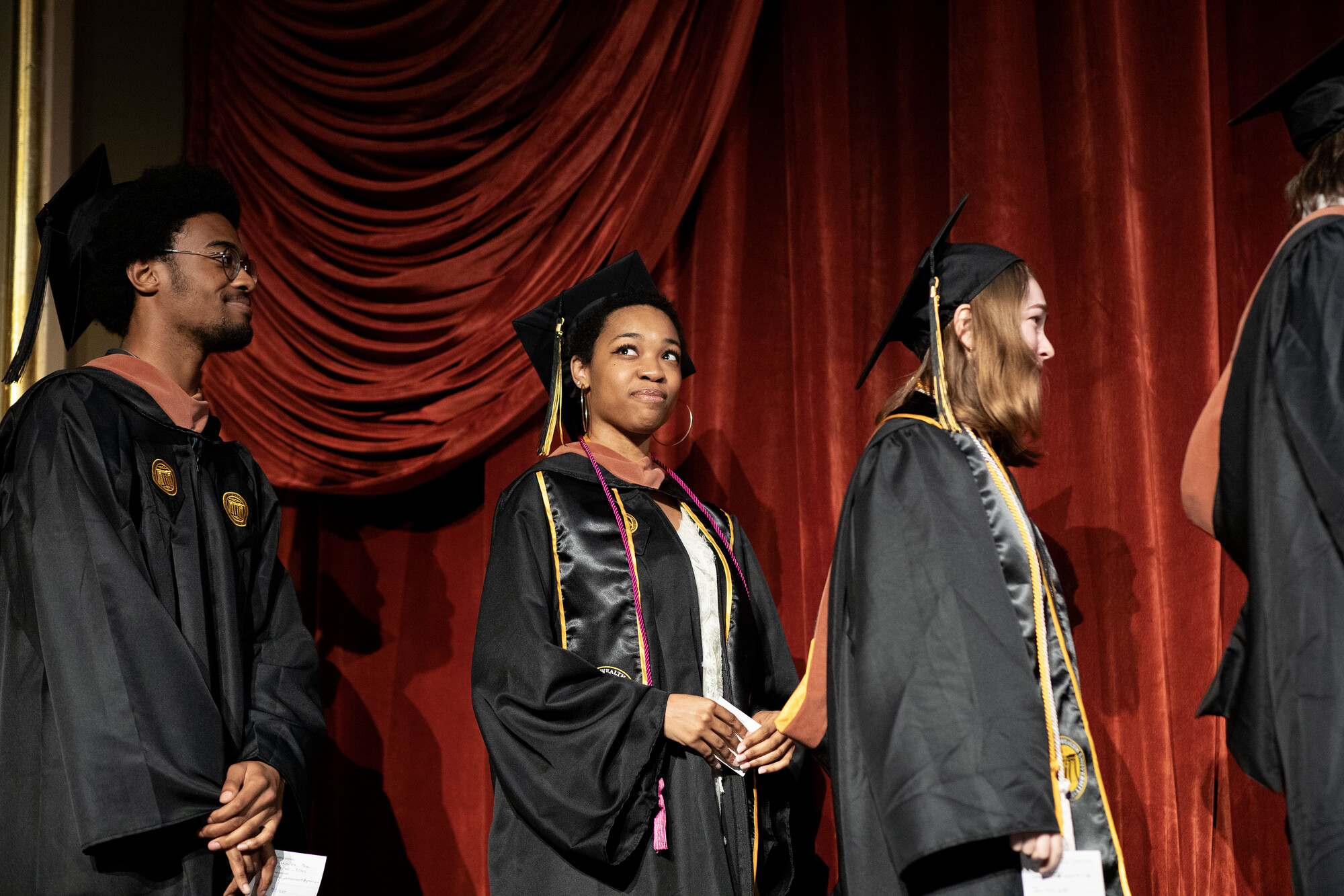 Students in regalia wait in line to receive their diplomas