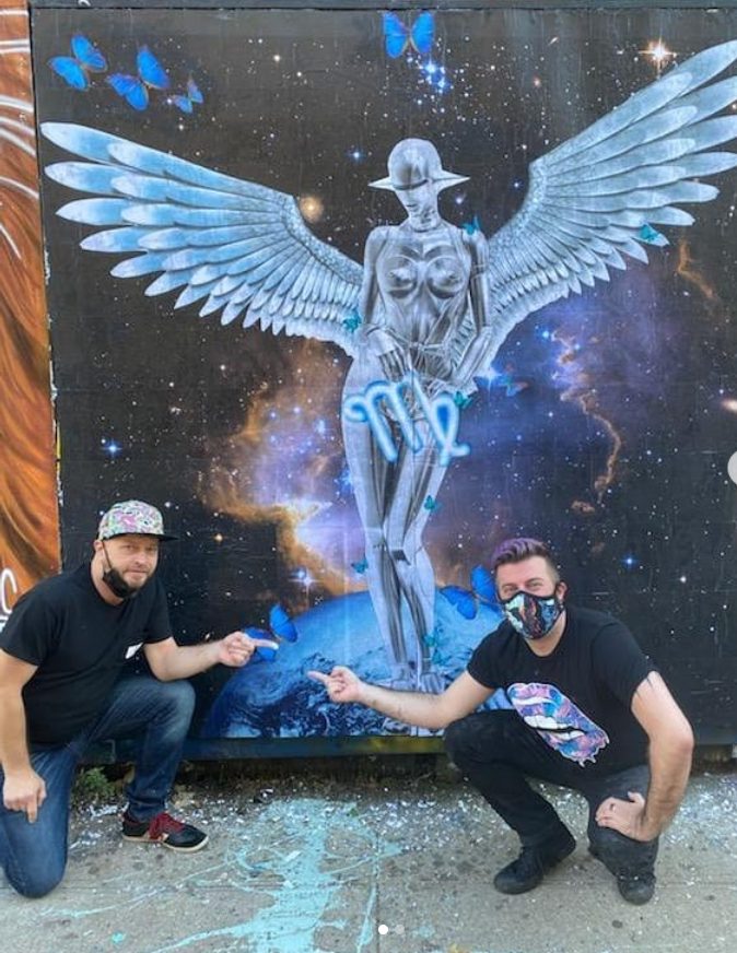 two men kneeling in front of mural