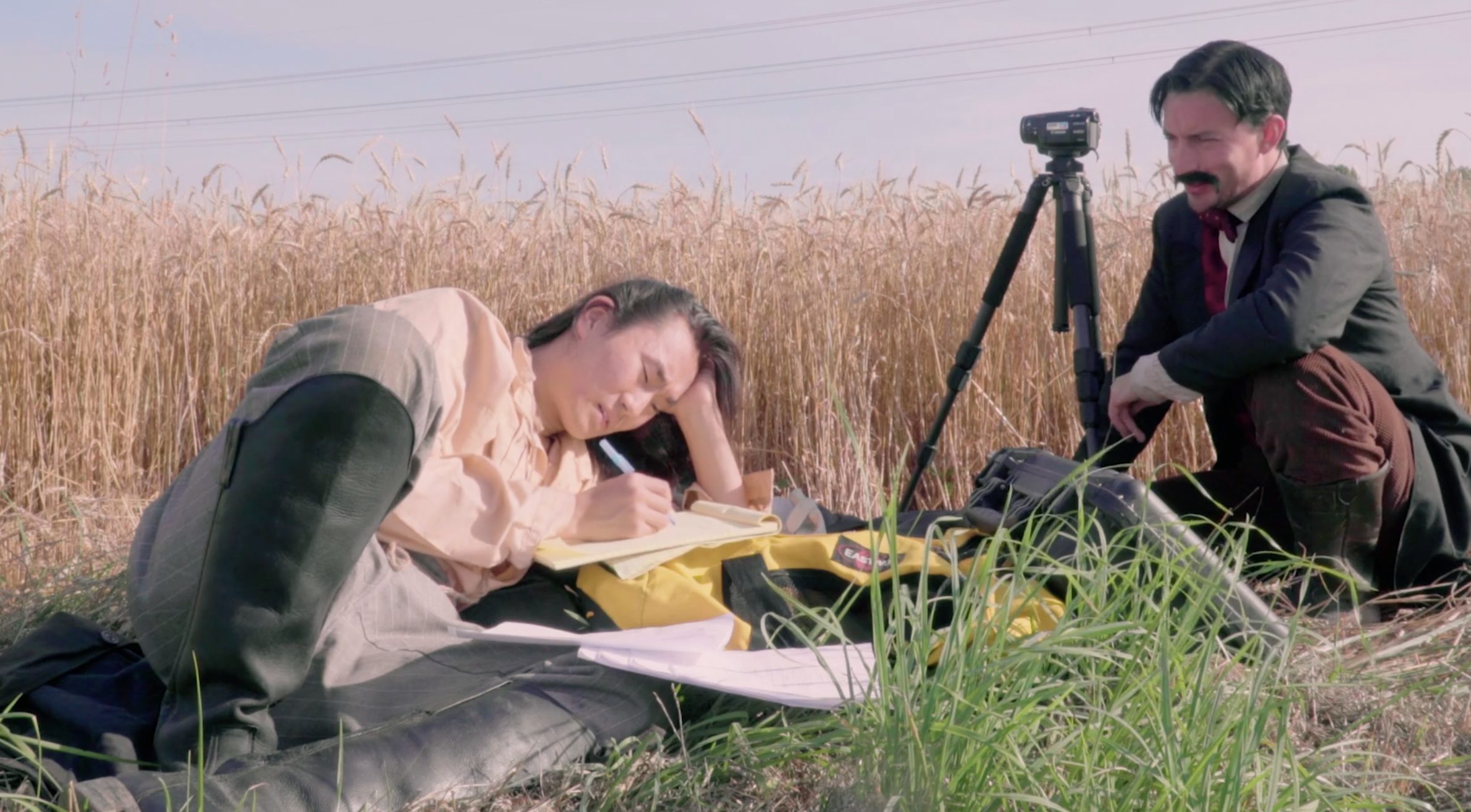 two men in grass with camera on tripod