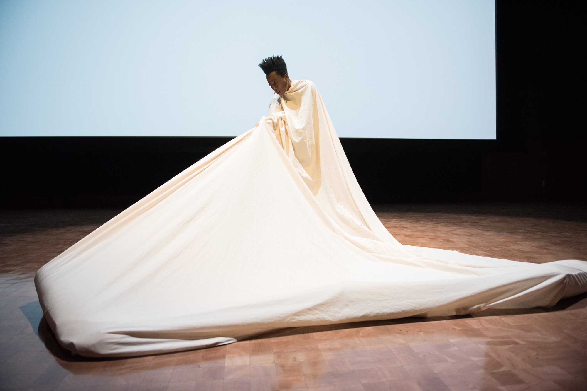 person dancing under a large, ballooning white fabric cloth