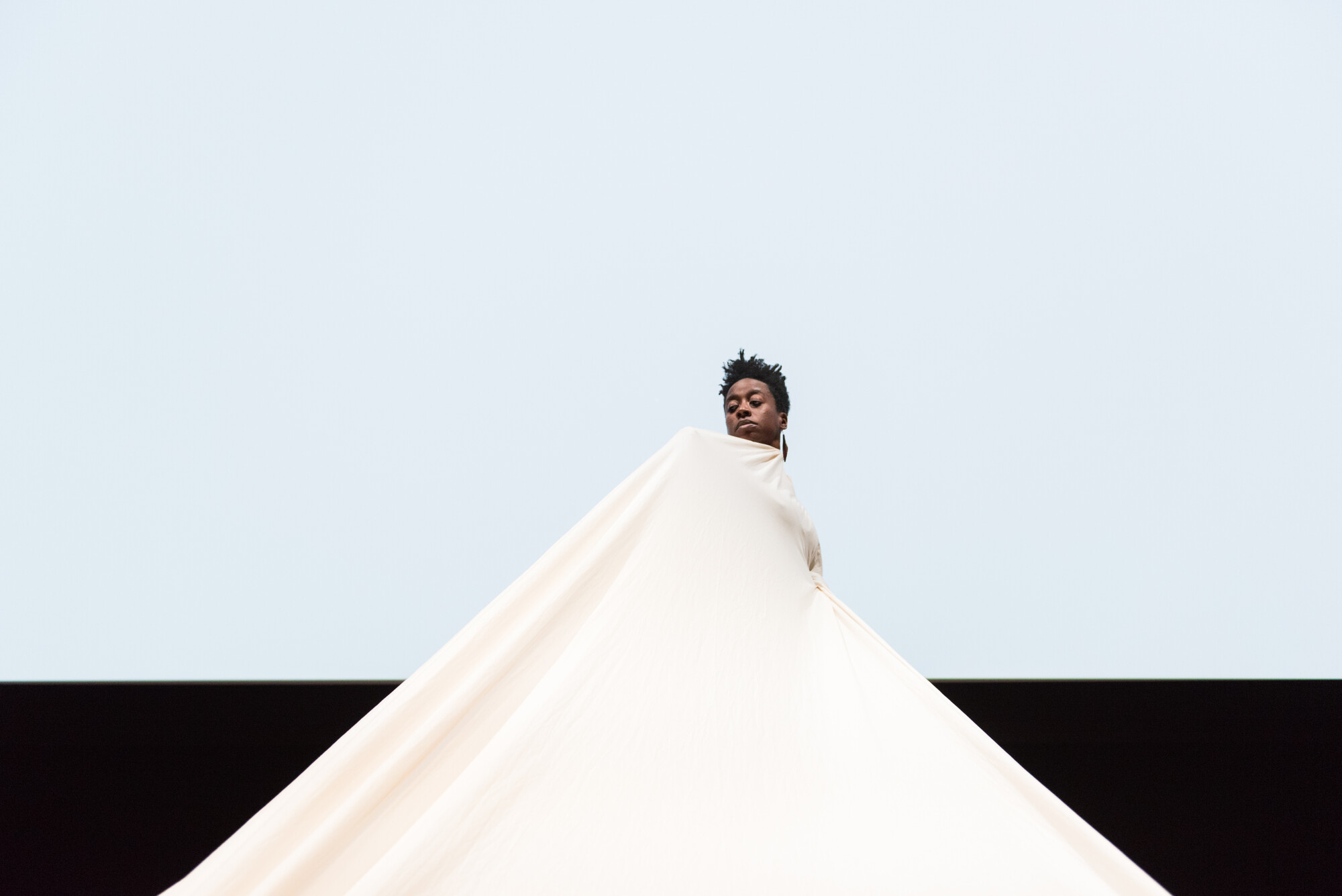 person dancing under a large, ballooning white fabric cloth