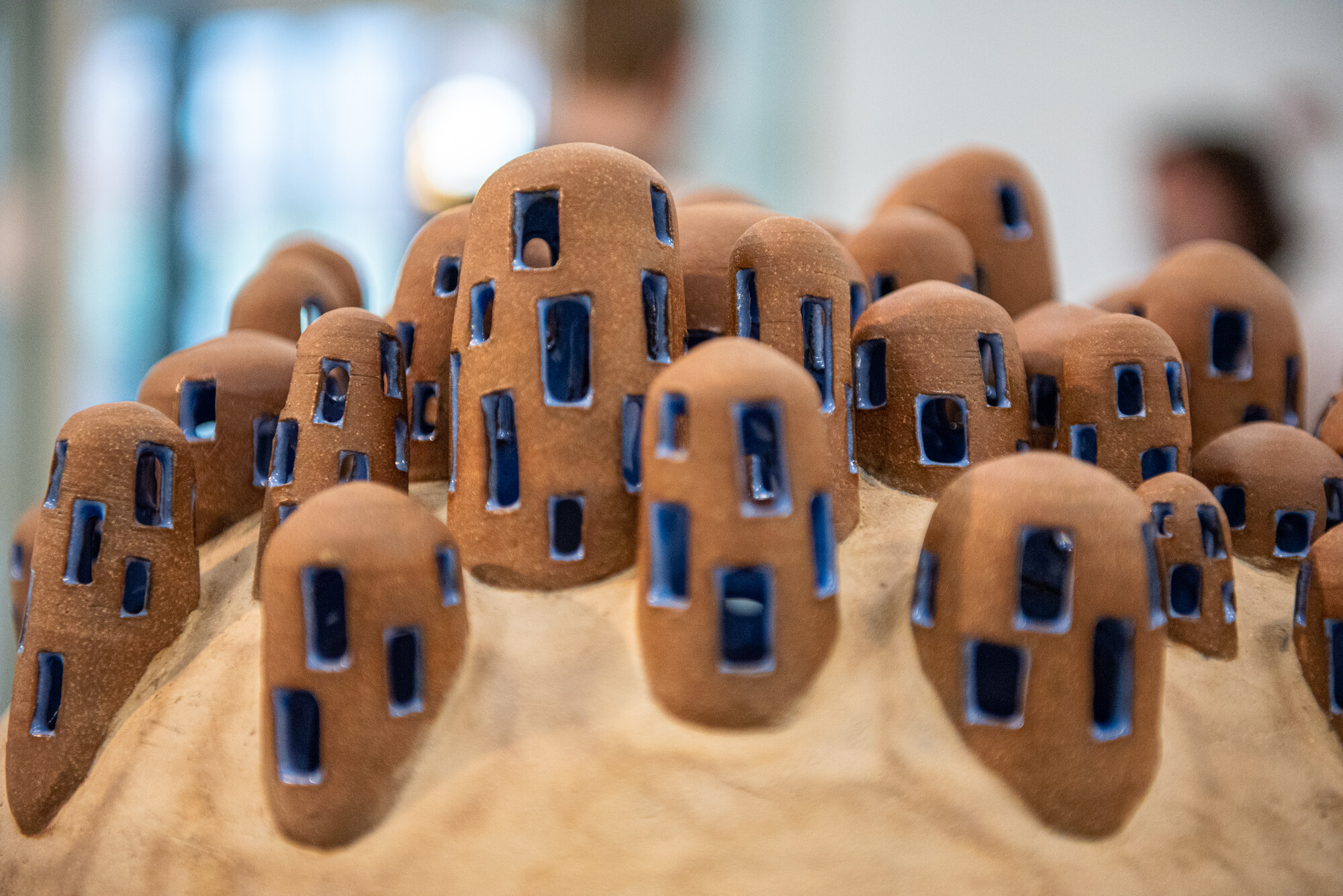 detail view of the ceramic piece showing organic protrustions on the top of the head piece with blue square patterns carved into it