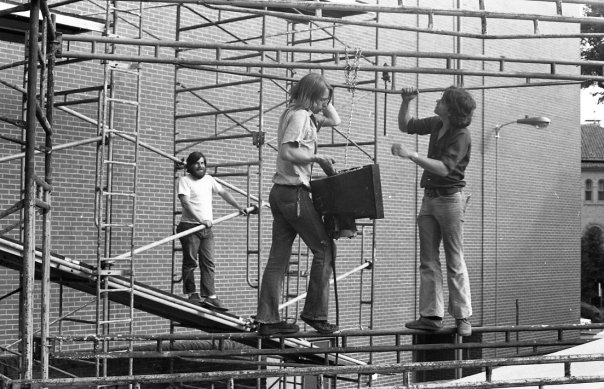 three people standing on scaffolding