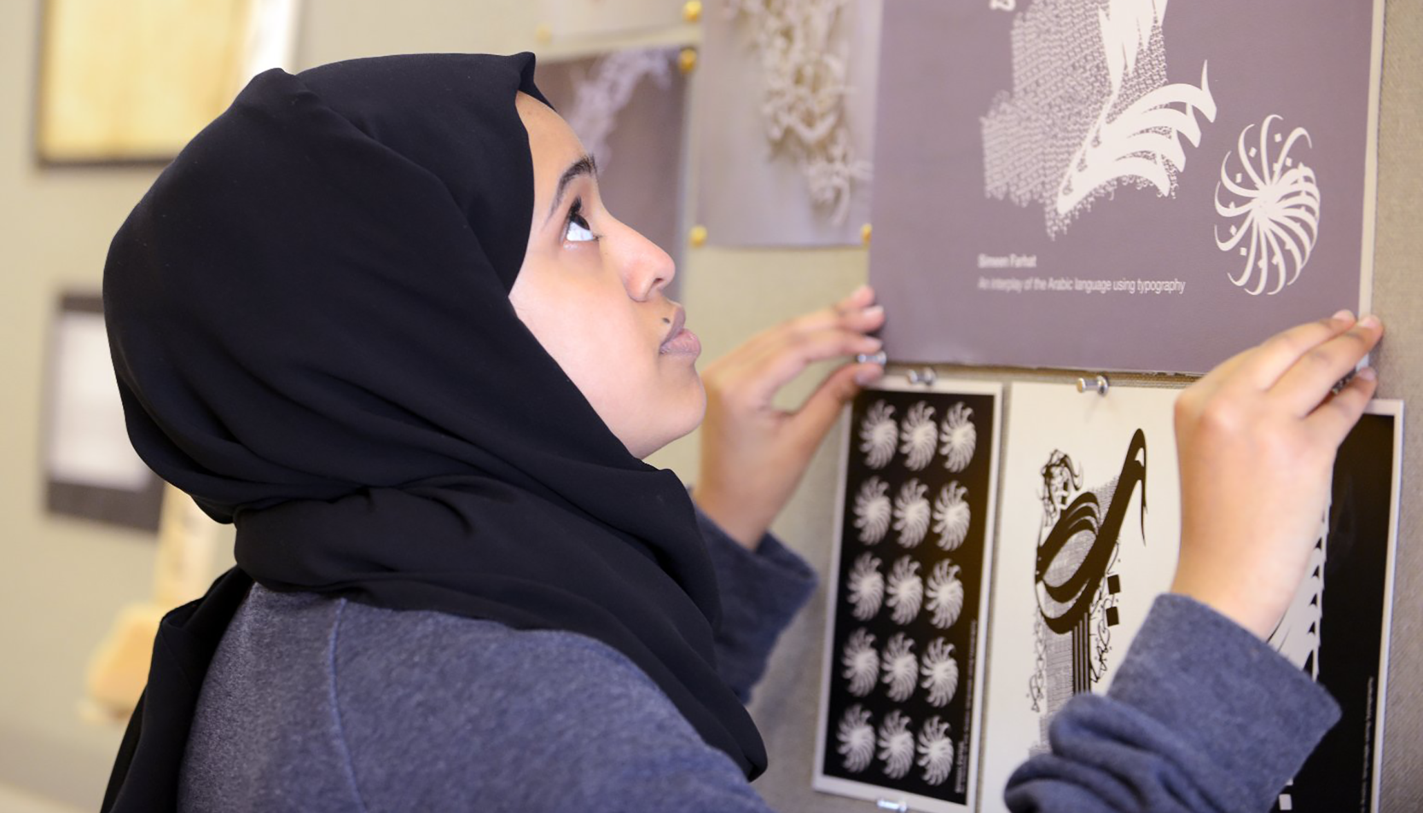 A woman pinning posters to a wall