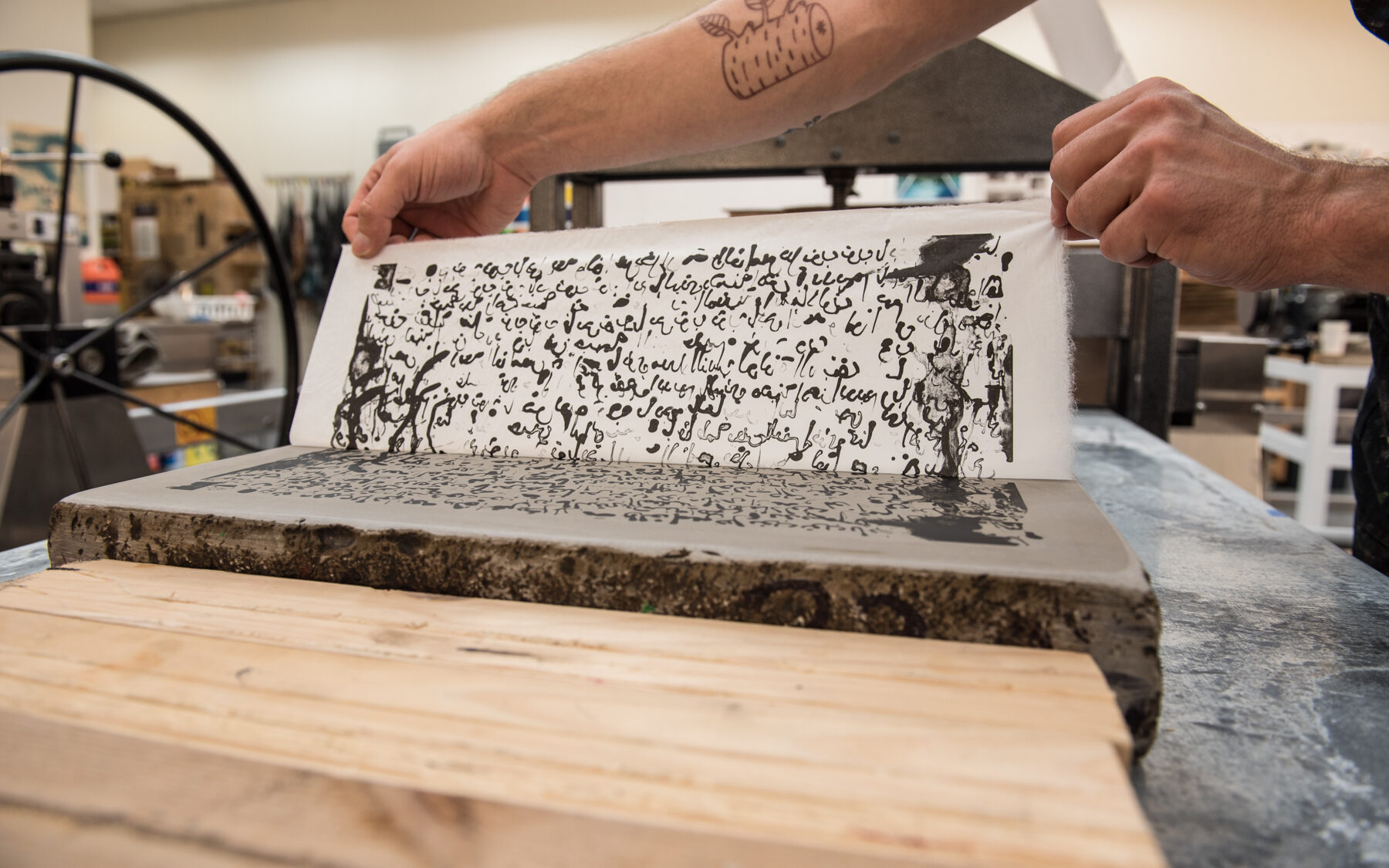 A student working on a printmaking project with Arabic characters