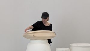 A sculpture student works on a piece in studio