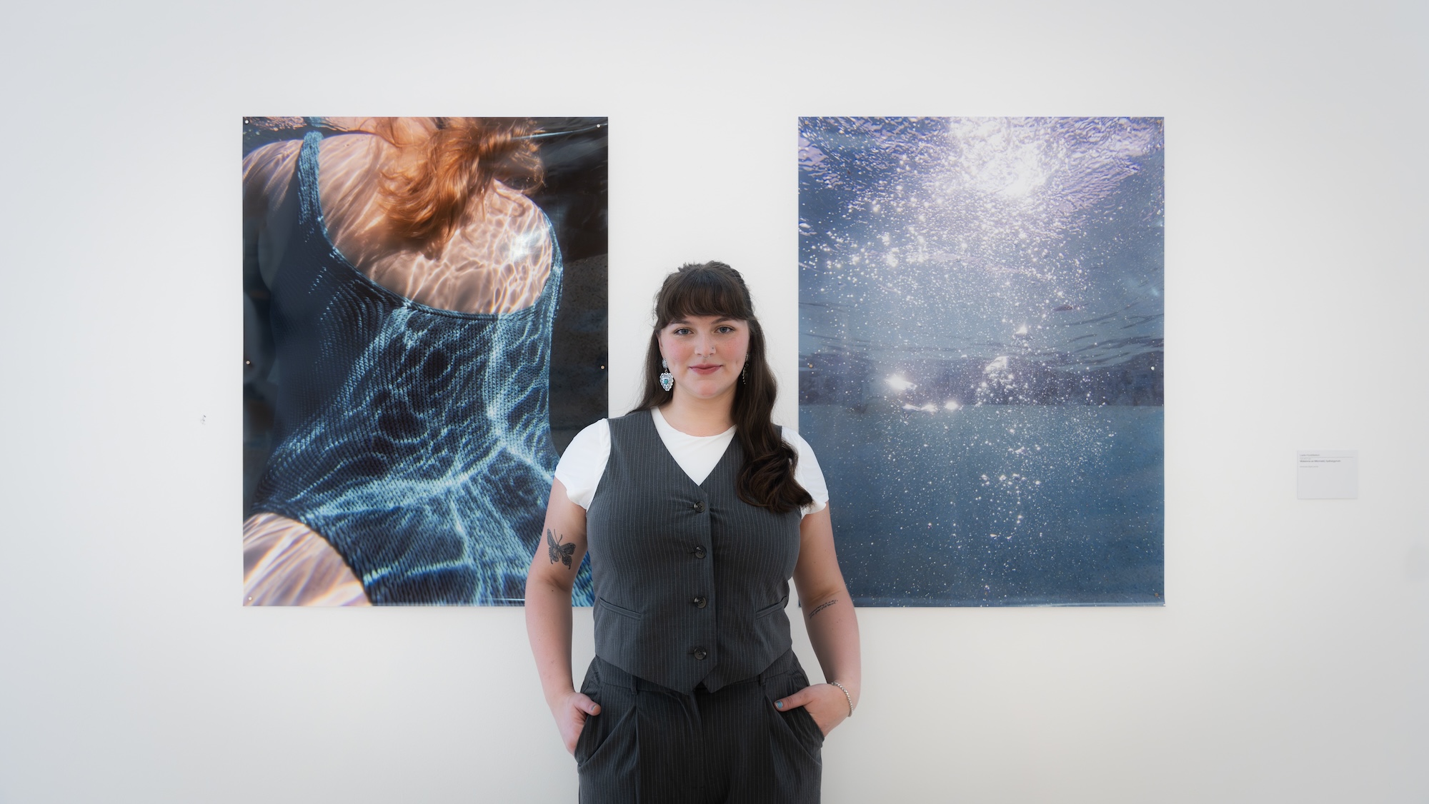 A woman standing in front of a wall adorned with various artworks in an art gallery setting.