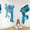 Photo of Ekaterina (Katya) Muromtsvea in her studio featuring her artwork: 10 foot floor to ceiling, two dimensional, painted renderings of life-sized, human silhouettes. Each focuses on a person holding or using different musical instruments