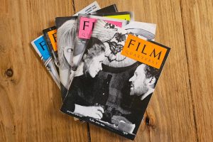 A group of magazines displaying various text on a table, with the words "FILM QUARTERLY" visible. The setting is indoors on a floor, surrounded by other paper products and books.