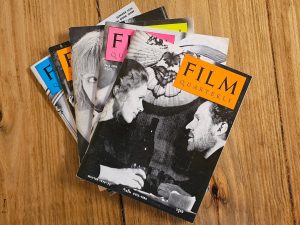 A group of magazines displaying various text on a table, with the words "FILM QUARTERLY" visible. The setting is indoors on a floor, surrounded by other paper products and books.