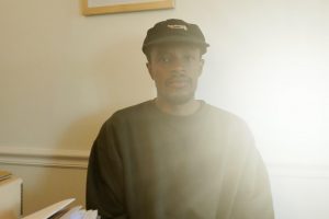 Photograph of artist Yusuf Hassan sitting at a table