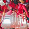 A ceiling of a room as a canopy of white, red, and pink soft sculptures dangling down toward the viewer.