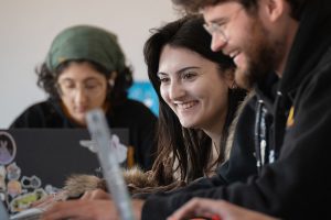 Students in classroom smiling looking at computer screen