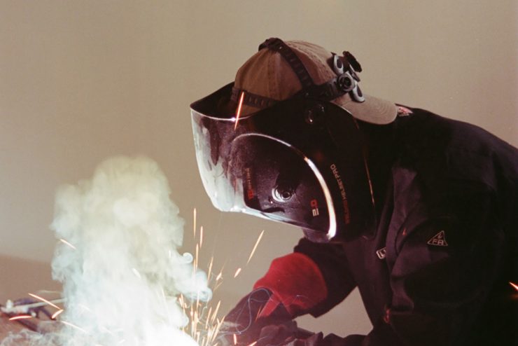 Em is wearing welding safety clothes while welding.