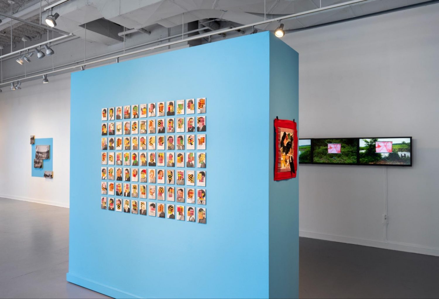 Artwork installed on a blue wall in the middle of a gallery