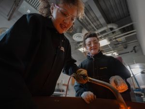Student and faculty member are casting metal in the studio.